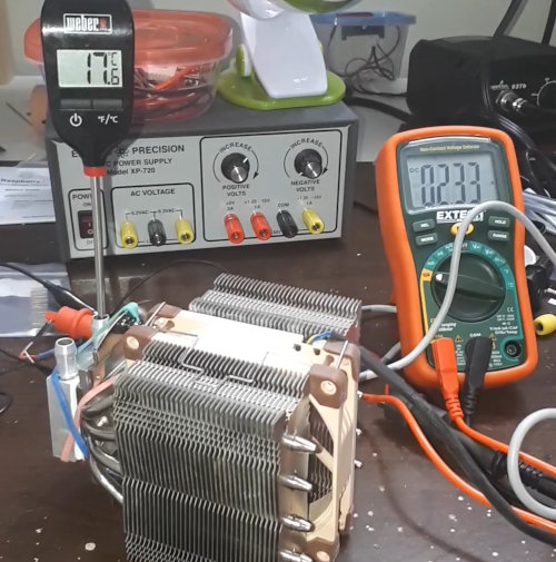 A photo of the meat thermometer probe in the water block and the multimeter measuring current to peltier